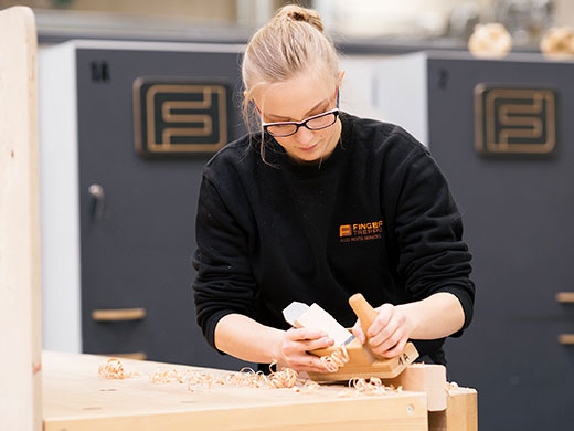 Tischlerin hobelt Holz